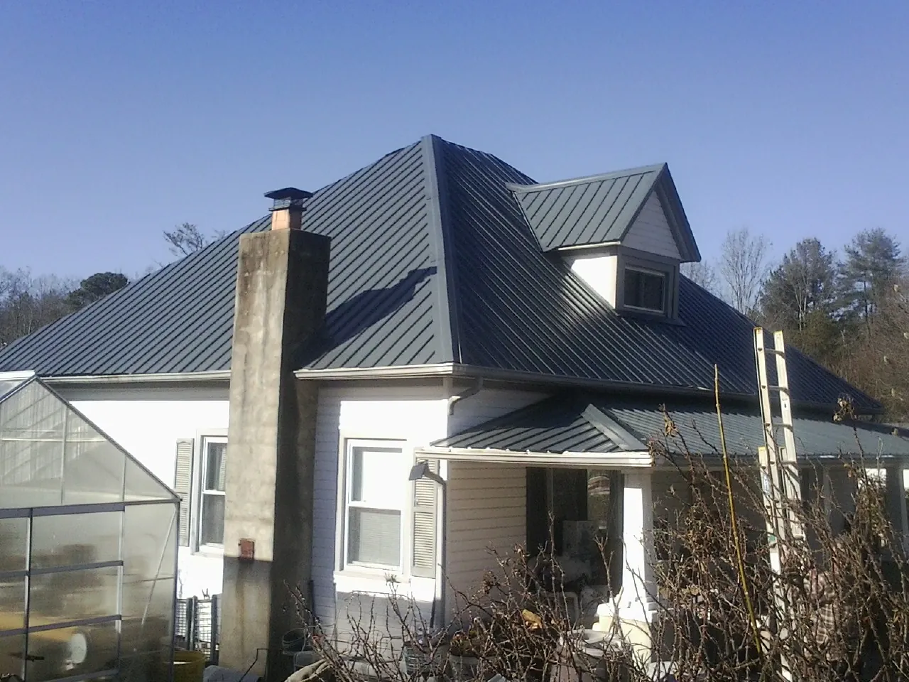 Dark blue standing seam metal roof on a white farmhouse with dormer — Slate & Tile Roof Repair by Roofing Brothers in Olivehill