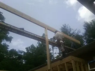 Carpenter setting a ridge beam over a new addition frame — Ice Dam Removal by Roofing Brothers in Olivehill