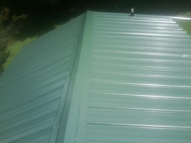 New green metal panels meeting at the ridge of a roof — Flat Roof Repair work by our crew in Olivehill