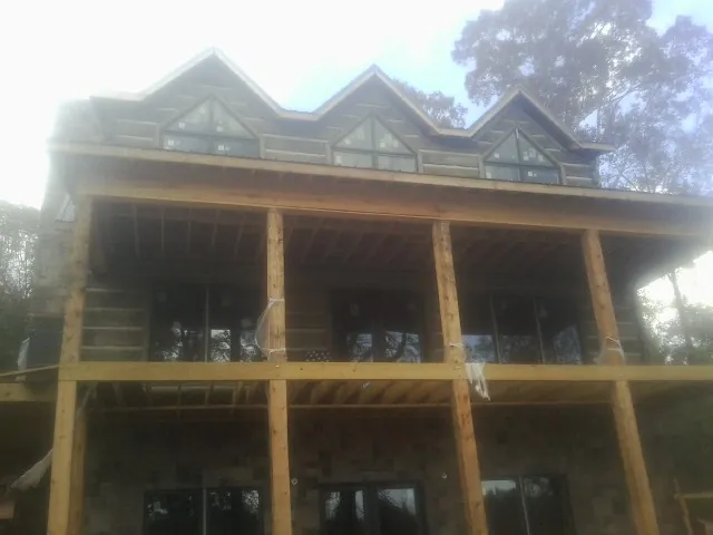 Dormers and porch framing on a large log home under construction — Roof Coating work by our crew in Olivehill