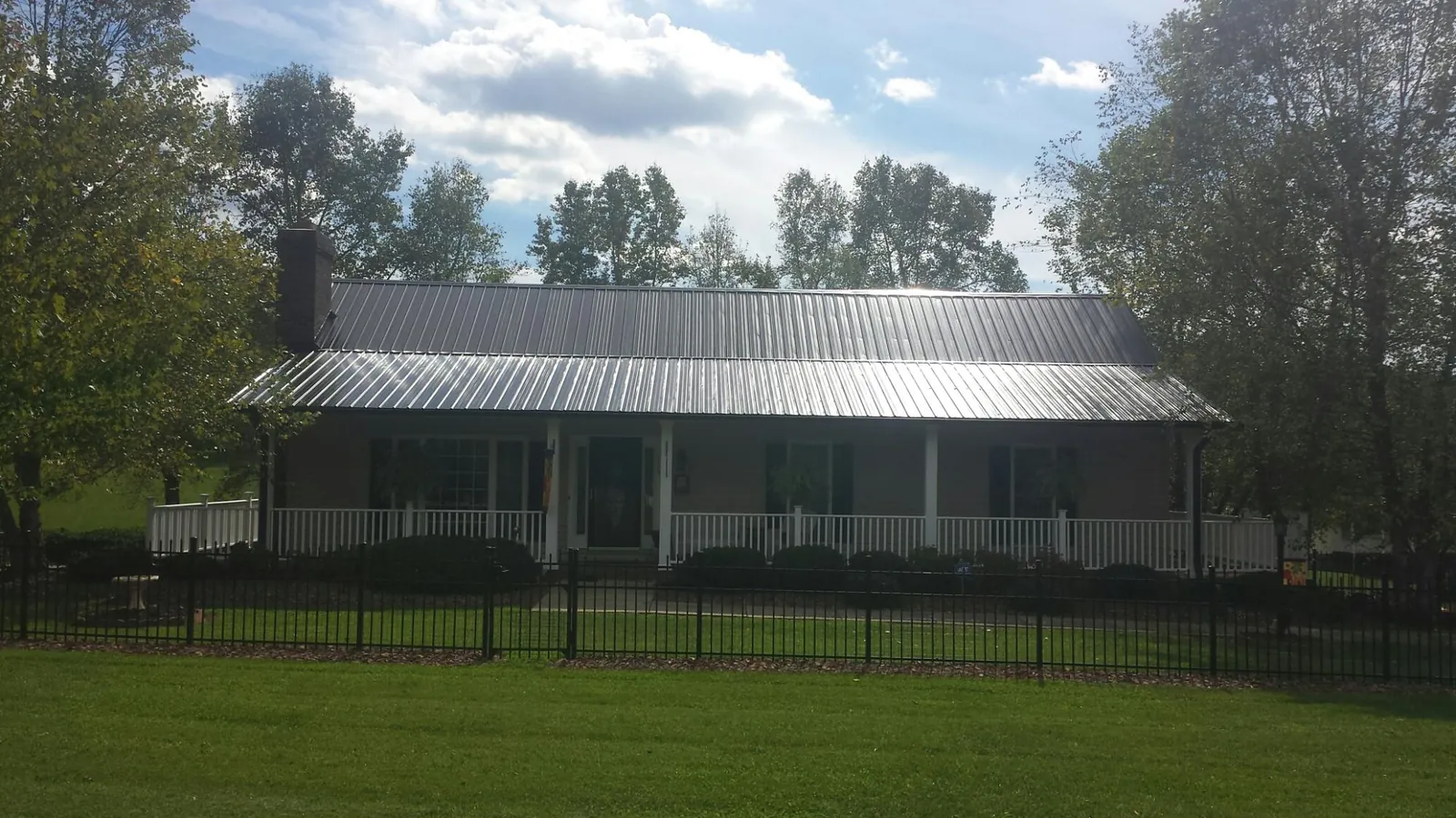 Gray metal roof on a brick ranch with a full width front porch — Gutter Guard Installation work by our crew in Olivehill