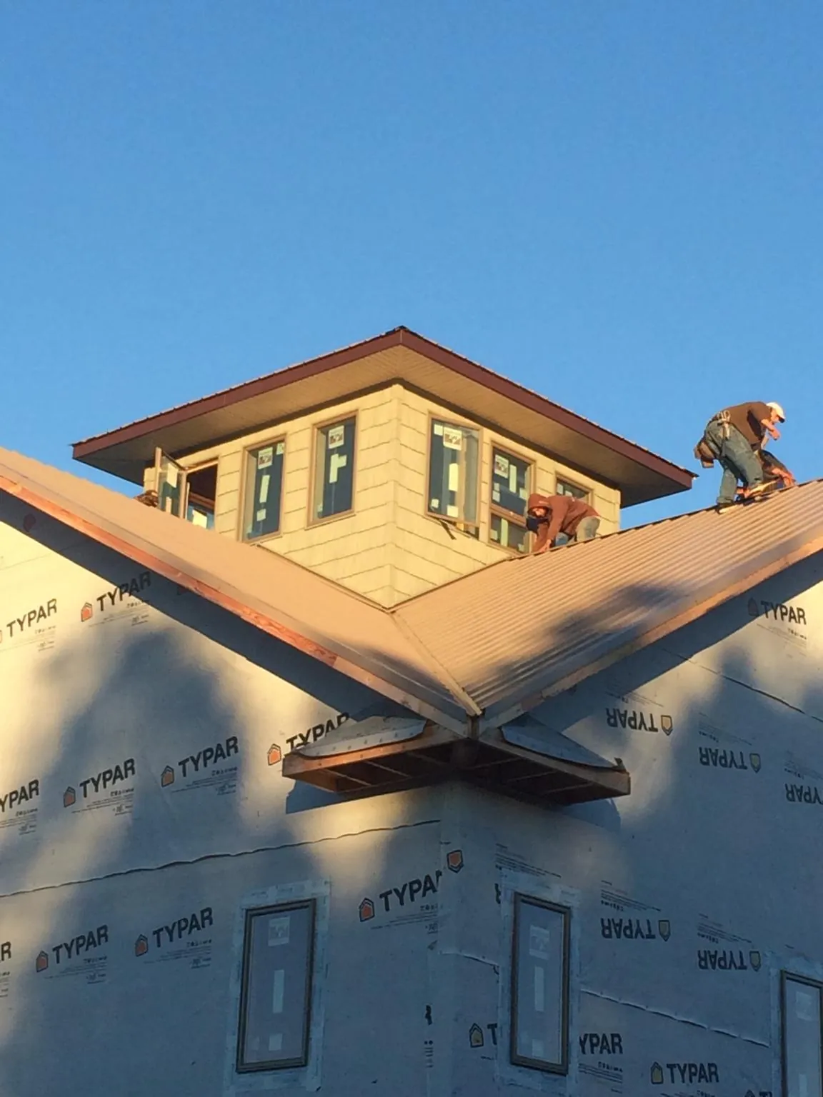 Roofers working around a rooftop cupola on a new metal roof at sunset — Roof Waterproofing in Olivehill by Roofing Brothers